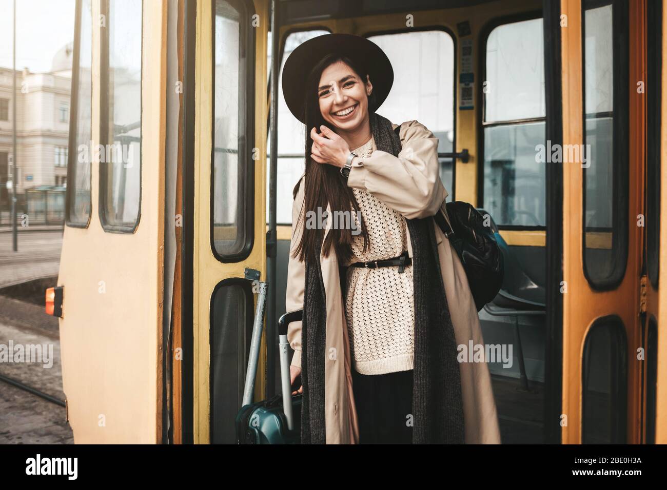 La ragazza, bellissima ed elegante, con valigia, si ferma dal tram Foto Stock