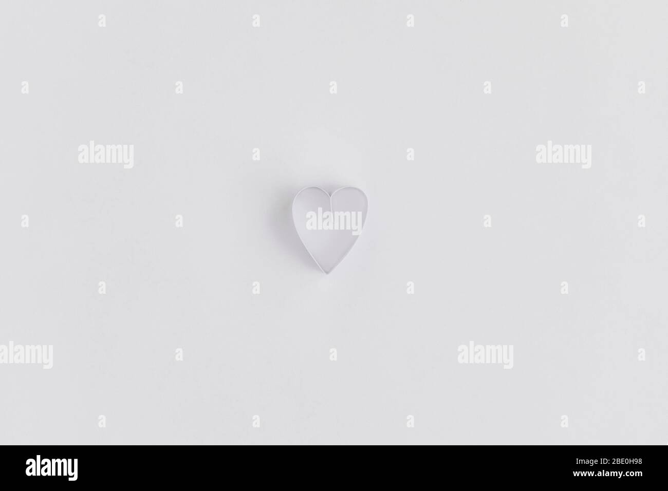 Un cuore fatto con striscia di carta annodata su sfondo di carta bianca Foto Stock
