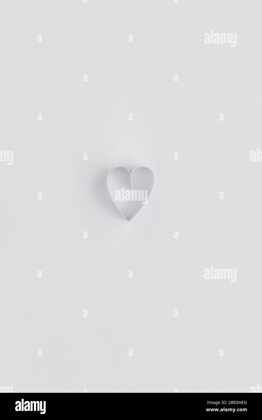 Un solo cuore fatto con striscia di carta annodata su bianco Foto Stock