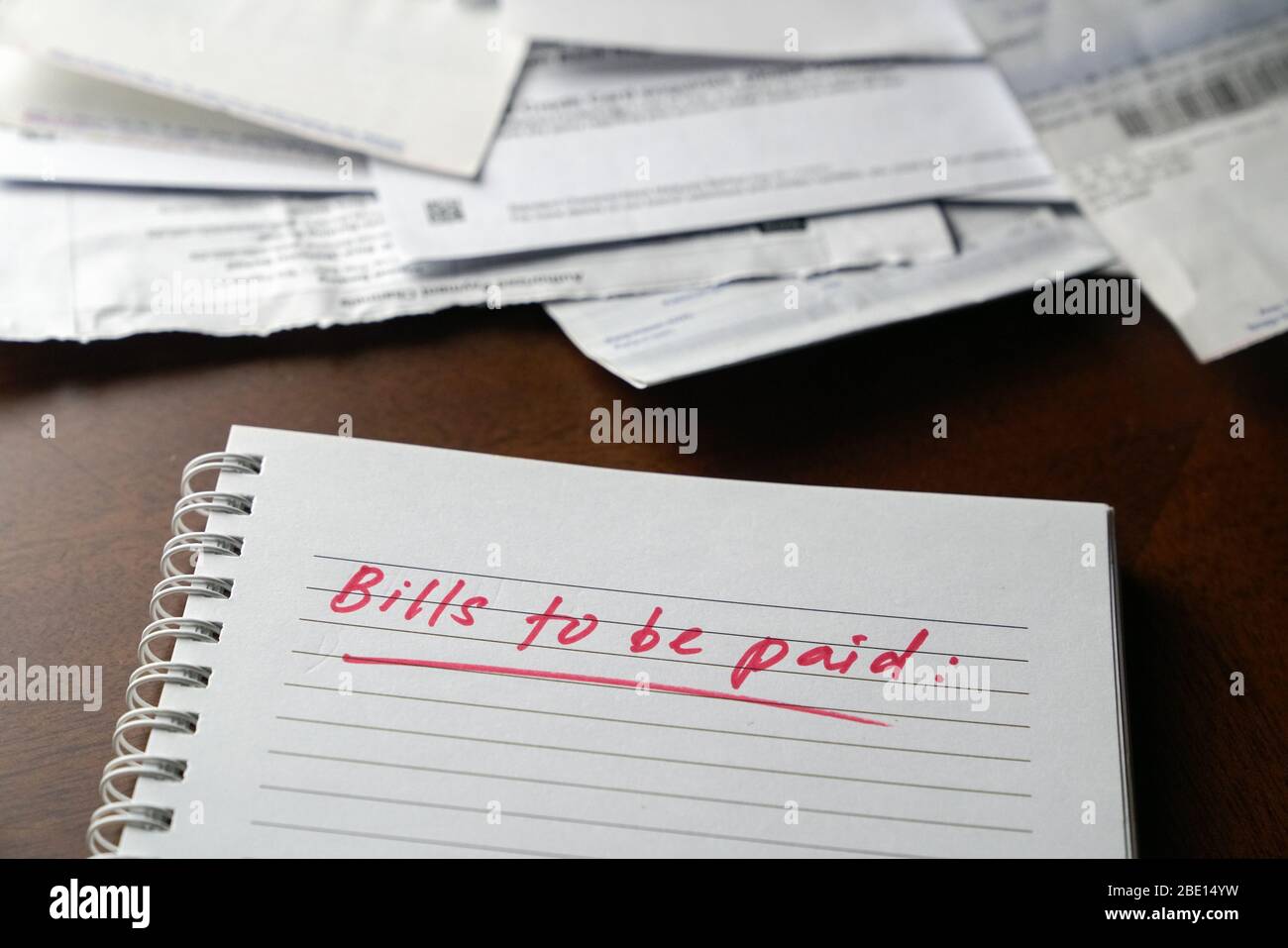 Fatture da pagare, scritte in rosso sul notebook con fatture e fatture in background. Concetto di disoccupazione o recessione. Foto Stock