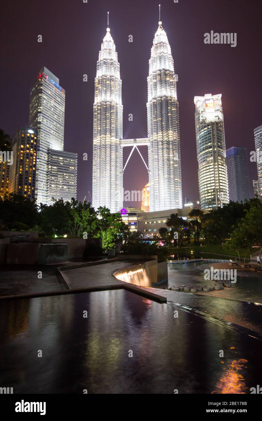 Foto di prima serata delle Torri Petronas a Kuala Lumpur, Malesia con riflessione in una piccola piscina fontana. Foto Stock