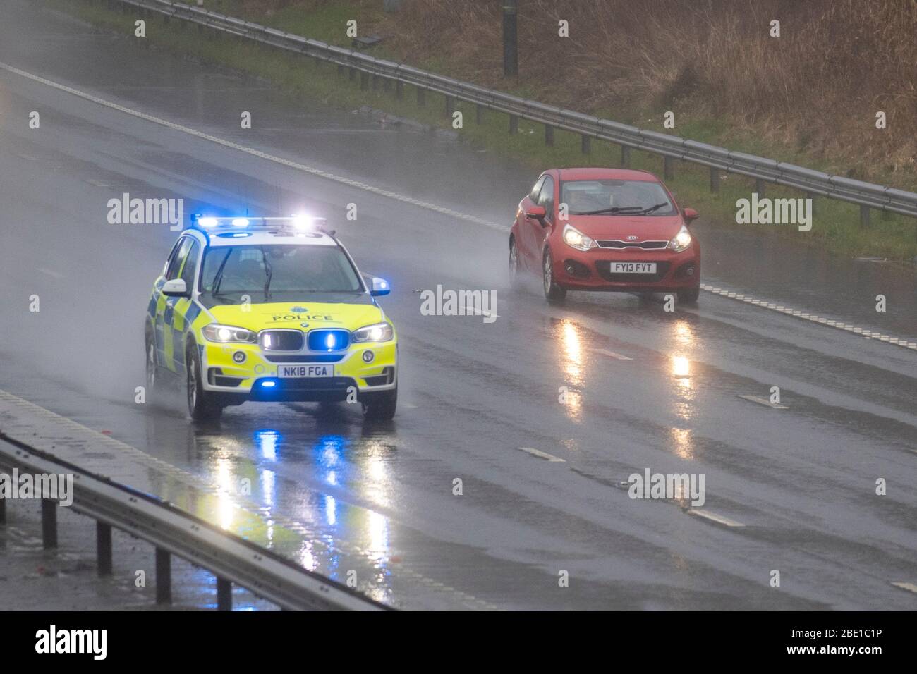 Polizia blu luci auto su 999 chiamata emegerncy risposta sulla M6 durante la doccia forte pioggia a Chorley, Lancashire. Pioggia intensa, docce a grandine, scarsa visibilità e tempo bagnato invernale di febbraio rendono le condizioni di guida molto difficili con superfici scivolose per gli automobilisti che viaggiano sull'autostrada M6. Foto Stock