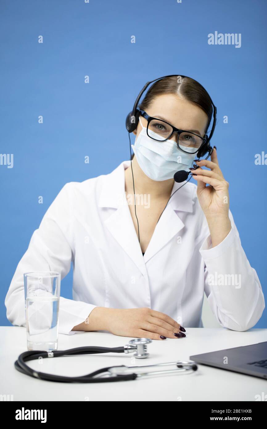 Giovane infermiera femminile in maschera medica con cuffia sulla consultazione del paziente Foto Stock