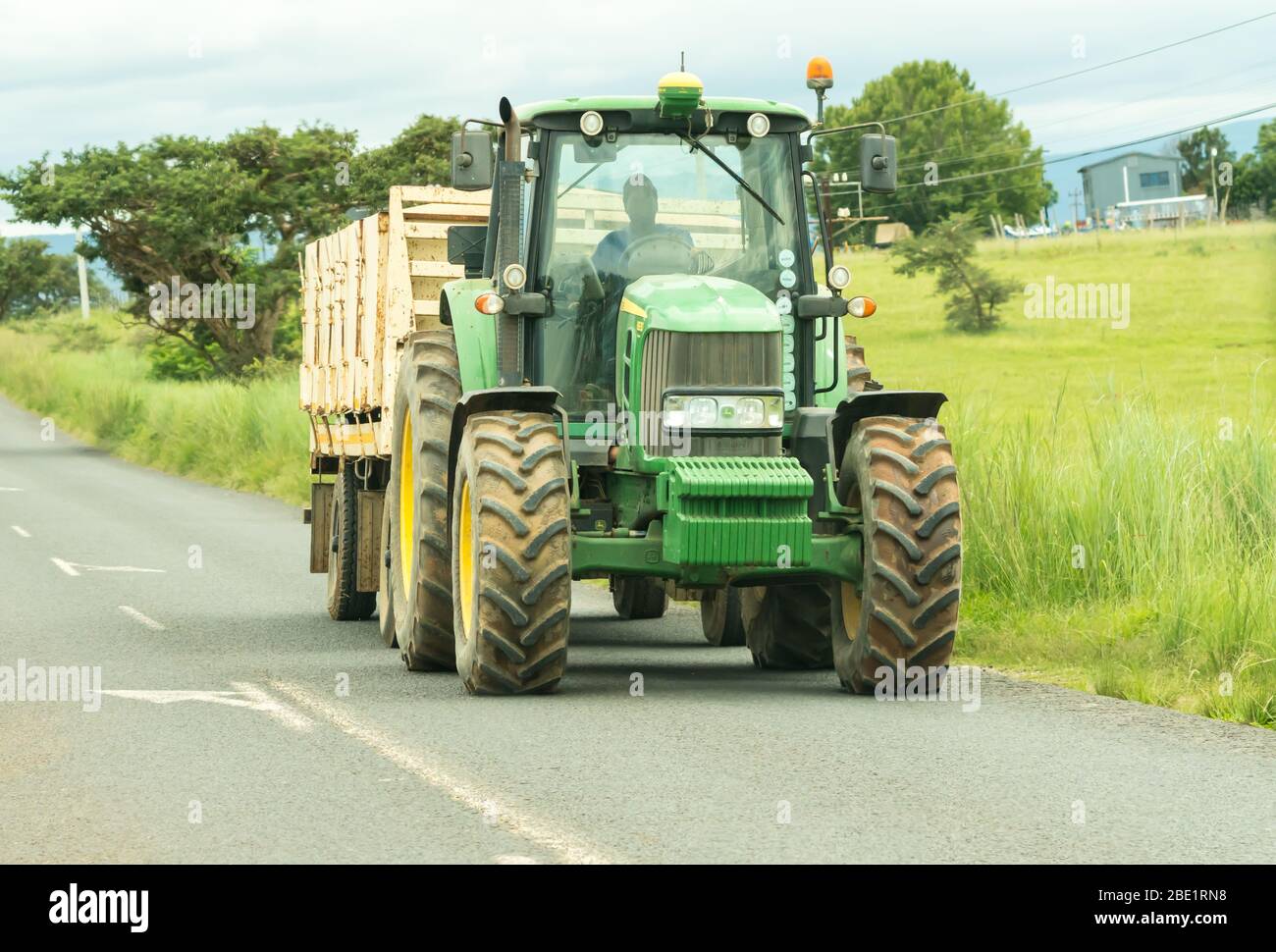 L'agricoltore africano guida un rimorchio trattore su una strada in un ambiente agricolo rurale e paesaggio a Kwazulu Natal, Sud Africa Foto Stock