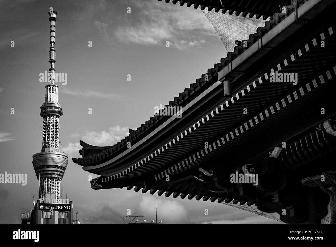 Il Tokyo Skytree alto 634 metri si erge dietro il tetto a tegole curve di un cancello del tempio di Sensō-ji ad Asakusa, Tokyo, Giappone. Alla base della torre, i cartelli pubblicizzano l'Hotel Trend e l'Hotel Mermaid Club. Foto Stock