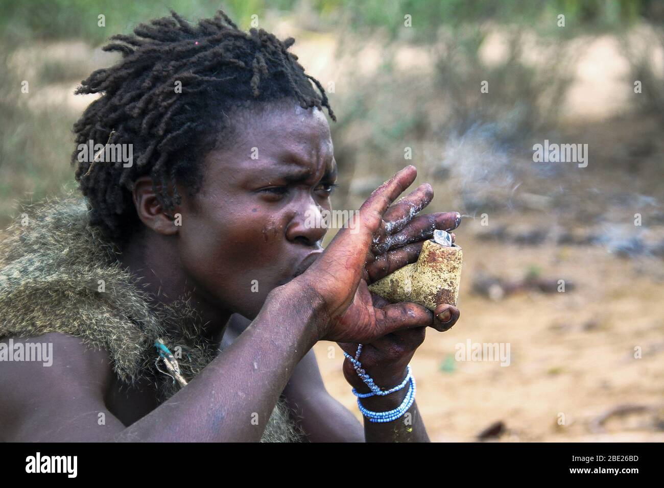Hadzabe uomo fumo da un tradizionale tubo di argilla fotografato vicino al lago Eyasi, Tanzania Africa Foto Stock