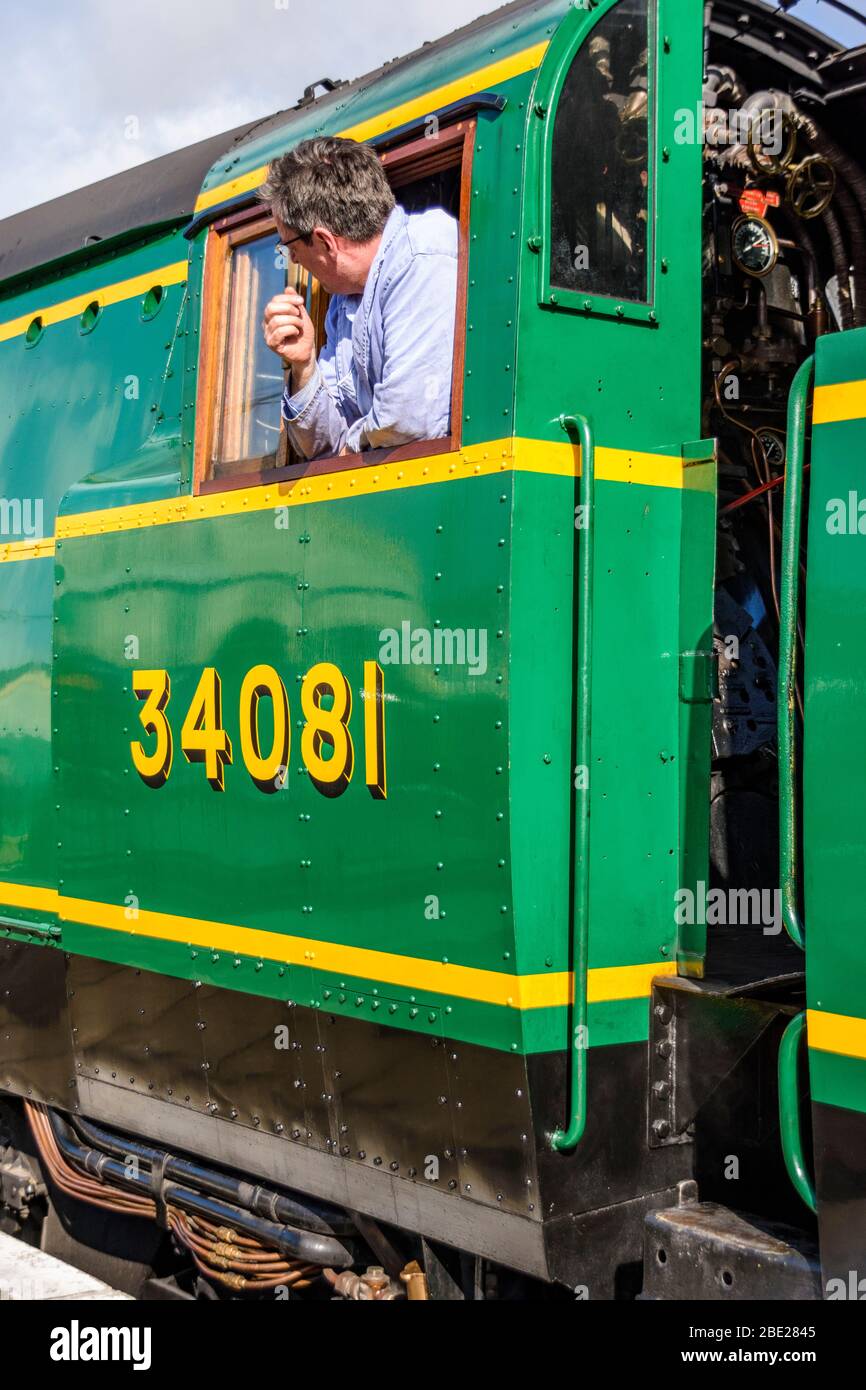 Il conducente si trova fuori dal finestrino della cabina della Classe Battle of Britain Steam loco 34081 92 Squadron Foto Stock