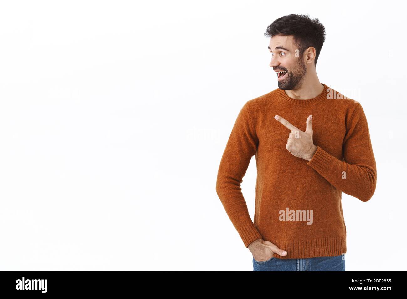 Ritratto di eccitato buon-osservare l'uomo adulto bearded, il tipo caucasico gira la testa e il dito di puntamento a sinistra con impressionato, emozione felice, vedendo la buona offerta Foto Stock