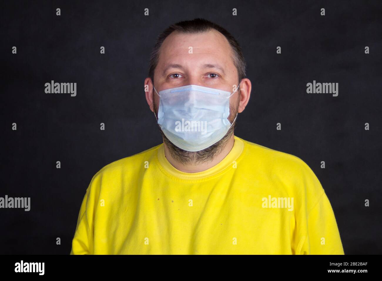 Uomo di mezza età in maschera monouso e giacca gialla Foto Stock