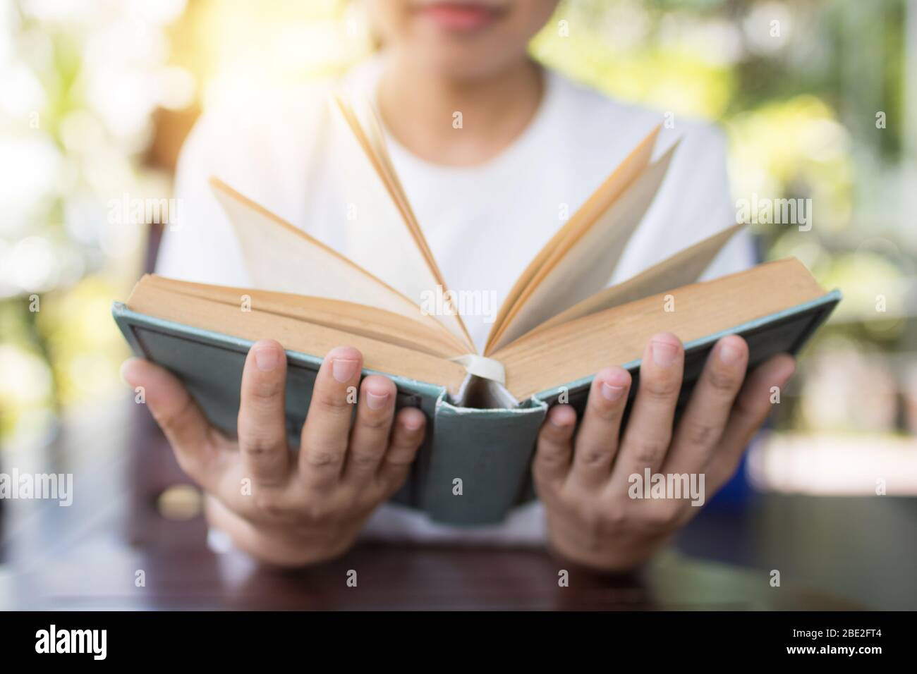 libro di tenuta aperto in due mani su tavola, saggezza e concetto di conoscenza Foto Stock libro di tenuta aperto in due mani su tavola, saggezza e concetto di conoscenza Foto Stock