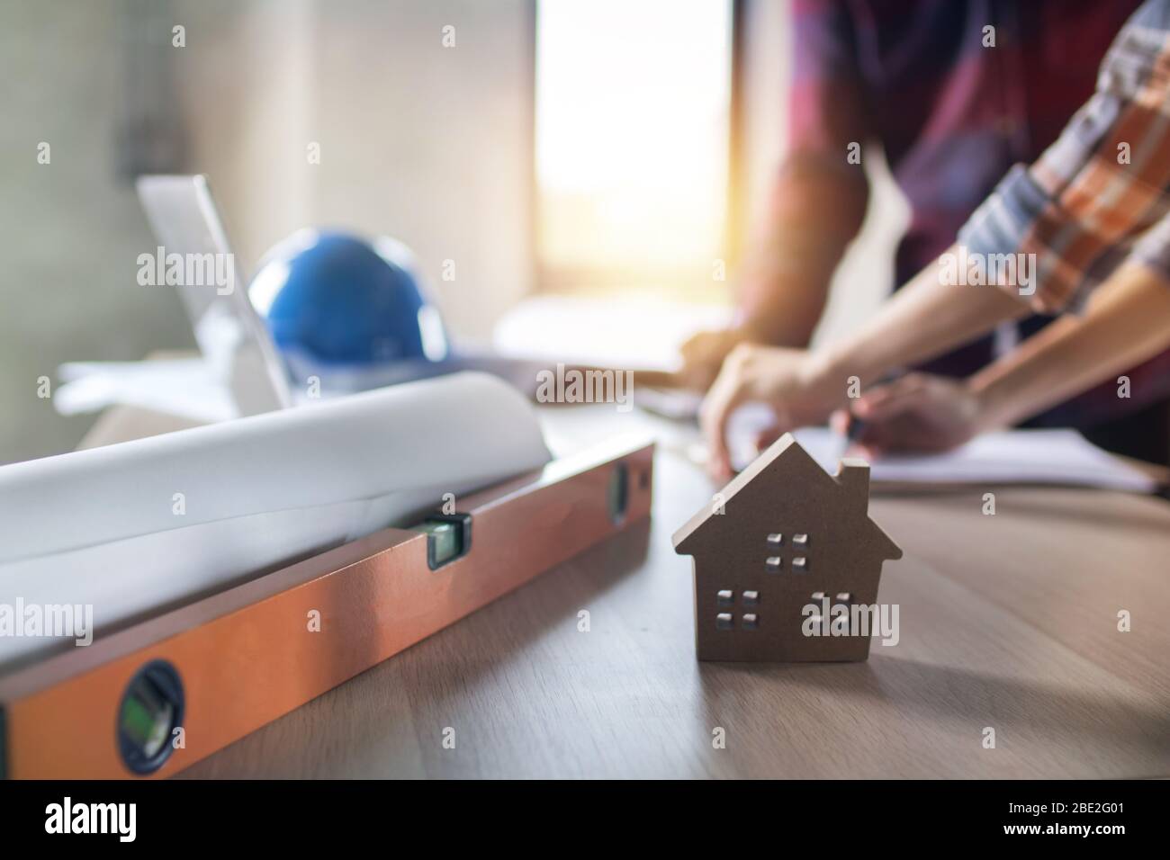 ingegnere planare e controllare su blueprint su sfondo tavolo di piccolo modello casa, concetto immobiliare Foto Stock