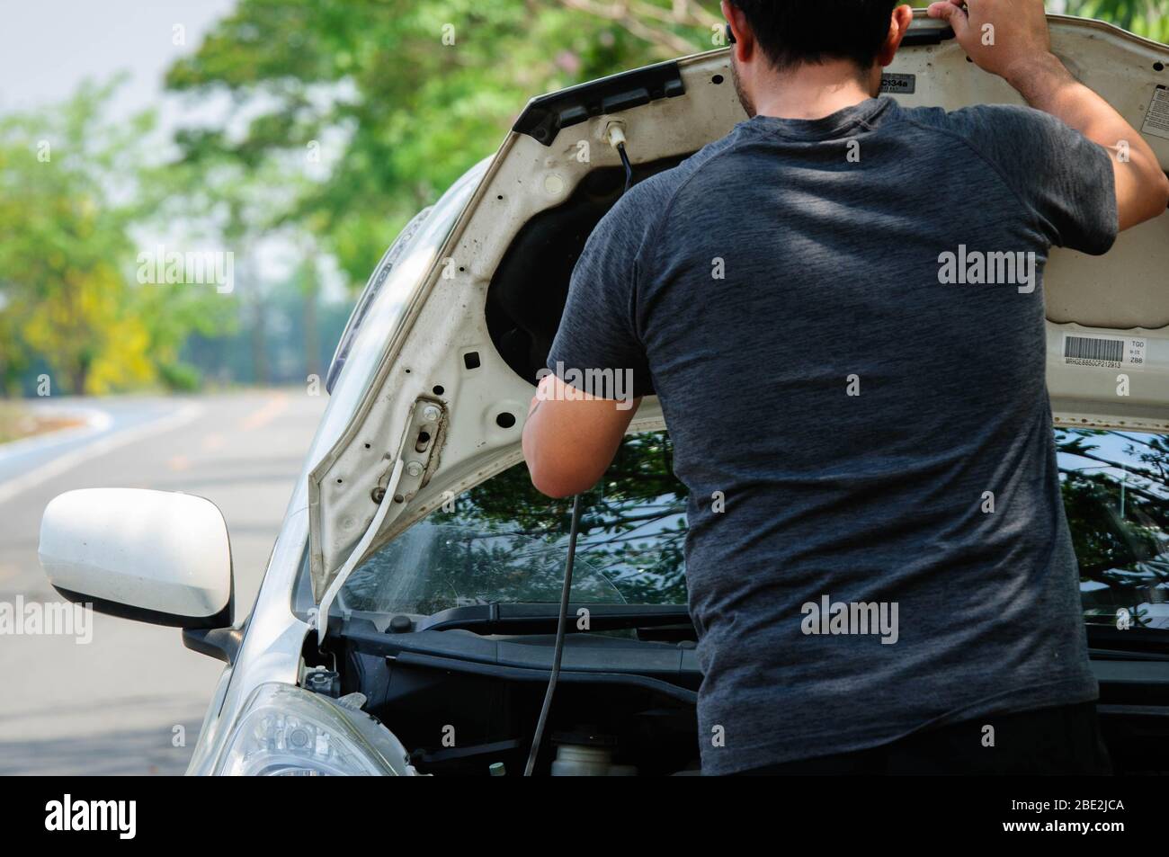 Un uomo che controlla il suo motore di automobile a bordo strada. Foto Stock