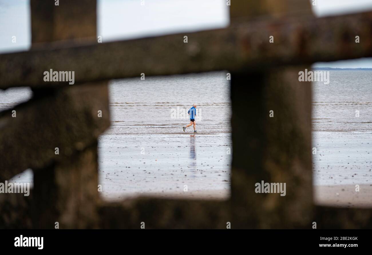 Portobello, Edimburgo. Scozia, Regno Unito. 11 aprile 2020. Il fine settimana di Pasqua sabato mattina il pubblico era all'aperto, esercitandosi e camminando sulla spiaggia di Portobello fuori di Edimburgo. La spiaggia e il lungomare erano molto tranquilli e la gente si stava esercitando a distanza sociale. Iain Masterton/Alamy Live News Foto Stock