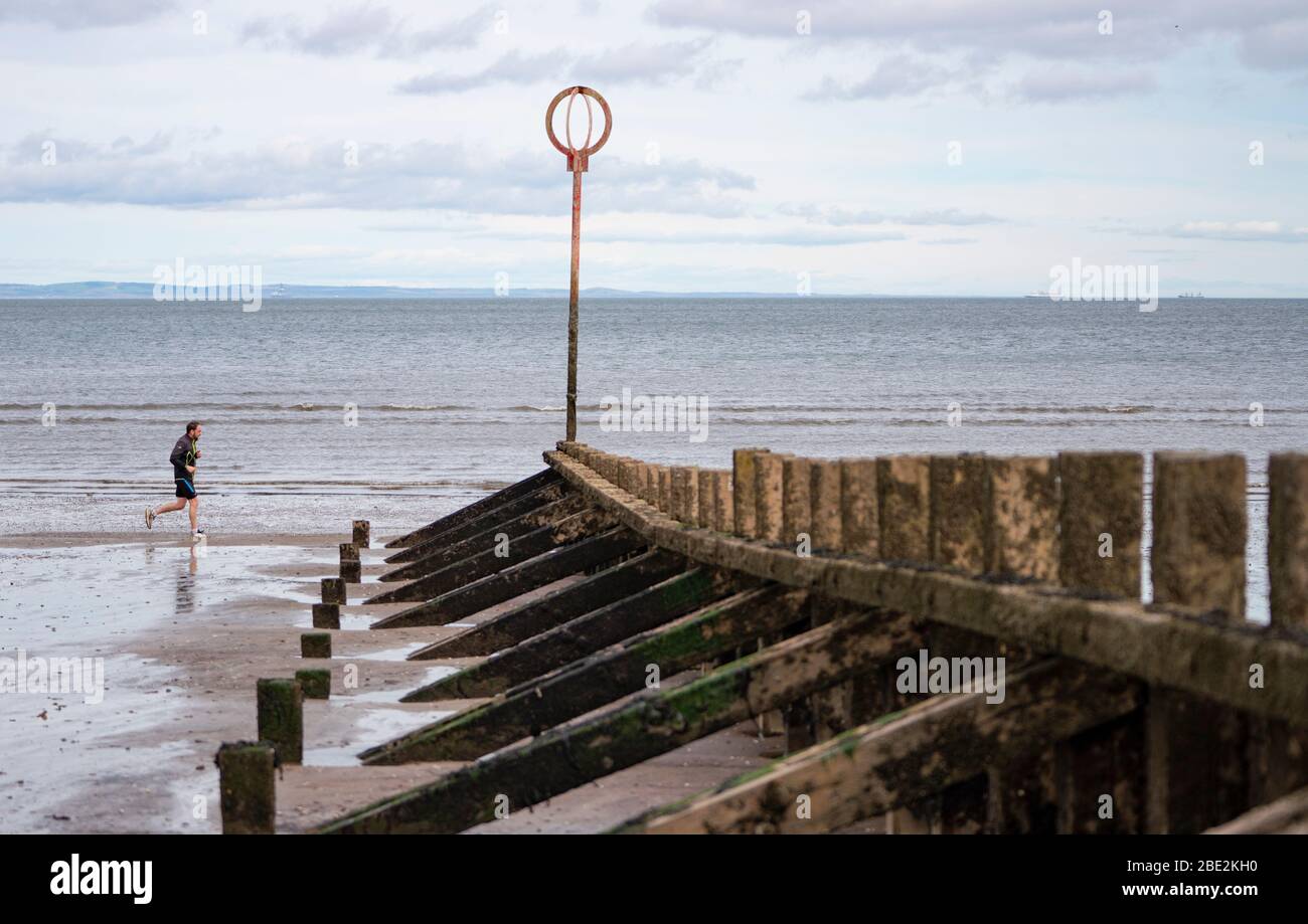 Portobello, Edimburgo. Scozia, Regno Unito. 11 aprile 2020. Il fine settimana di Pasqua sabato mattina il pubblico era all'aperto, esercitandosi e camminando sulla spiaggia di Portobello fuori di Edimburgo. La spiaggia e il lungomare erano molto tranquilli e la gente si stava esercitando a distanza sociale. Iain Masterton/Alamy Live News Foto Stock