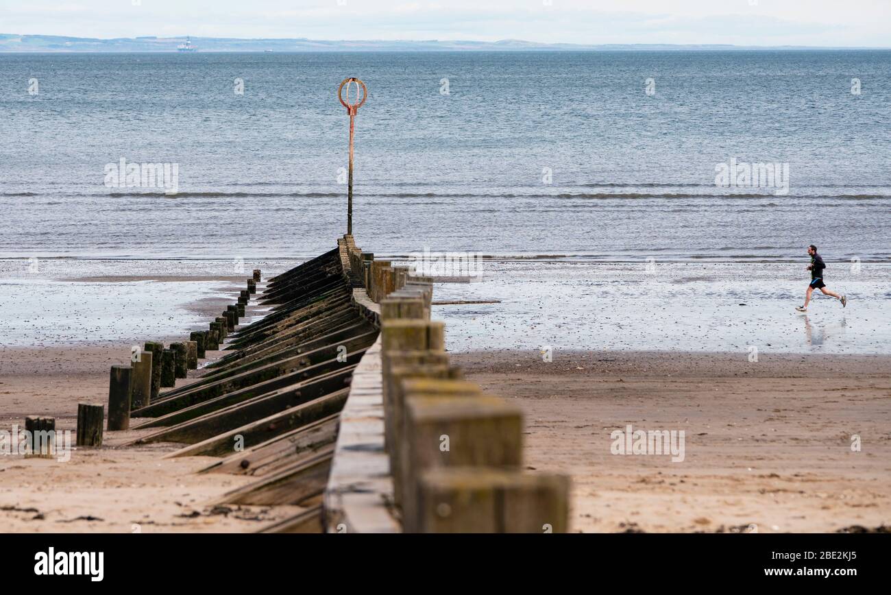 Portobello, Edimburgo. Scozia, Regno Unito. 11 aprile 2020. Il fine settimana di Pasqua sabato mattina il pubblico era all'aperto, esercitandosi e camminando sulla spiaggia di Portobello fuori di Edimburgo. La spiaggia e il lungomare erano molto tranquilli e la gente si stava esercitando a distanza sociale. Iain Masterton/Alamy Live News Foto Stock