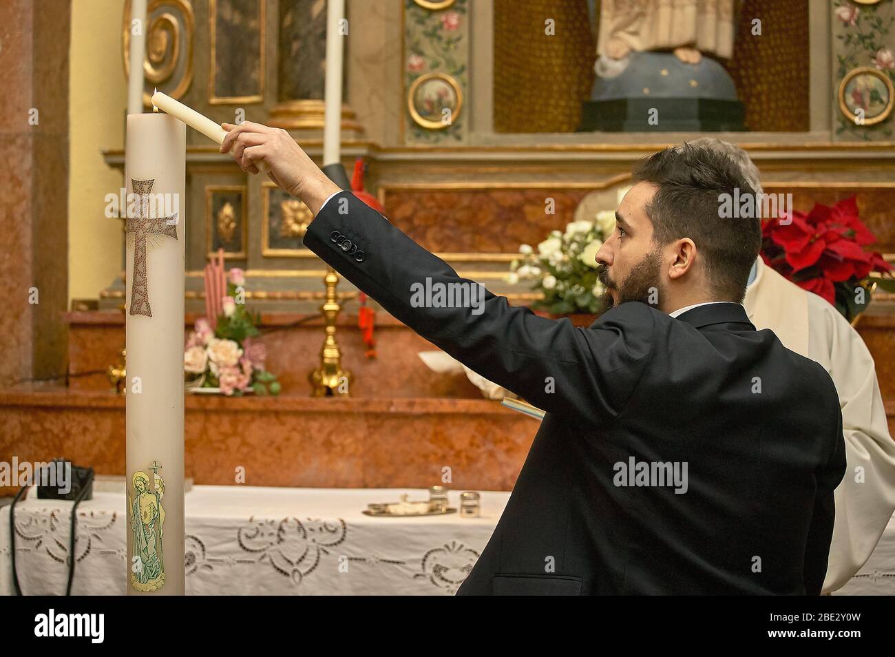 Il Padrino al battesimo tiene e accende la candela Foto stock - Alamy