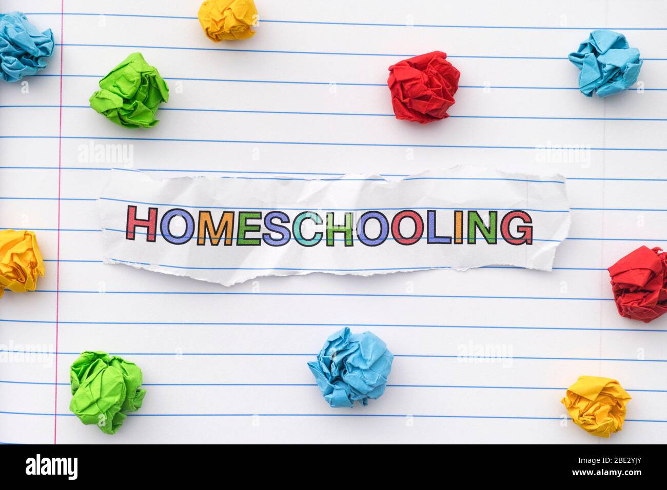La parola Homeschooling scritto su un foglio di notebook con alcune palle di carta stropicciati intorno ad esso. Primo piano. Foto Stock