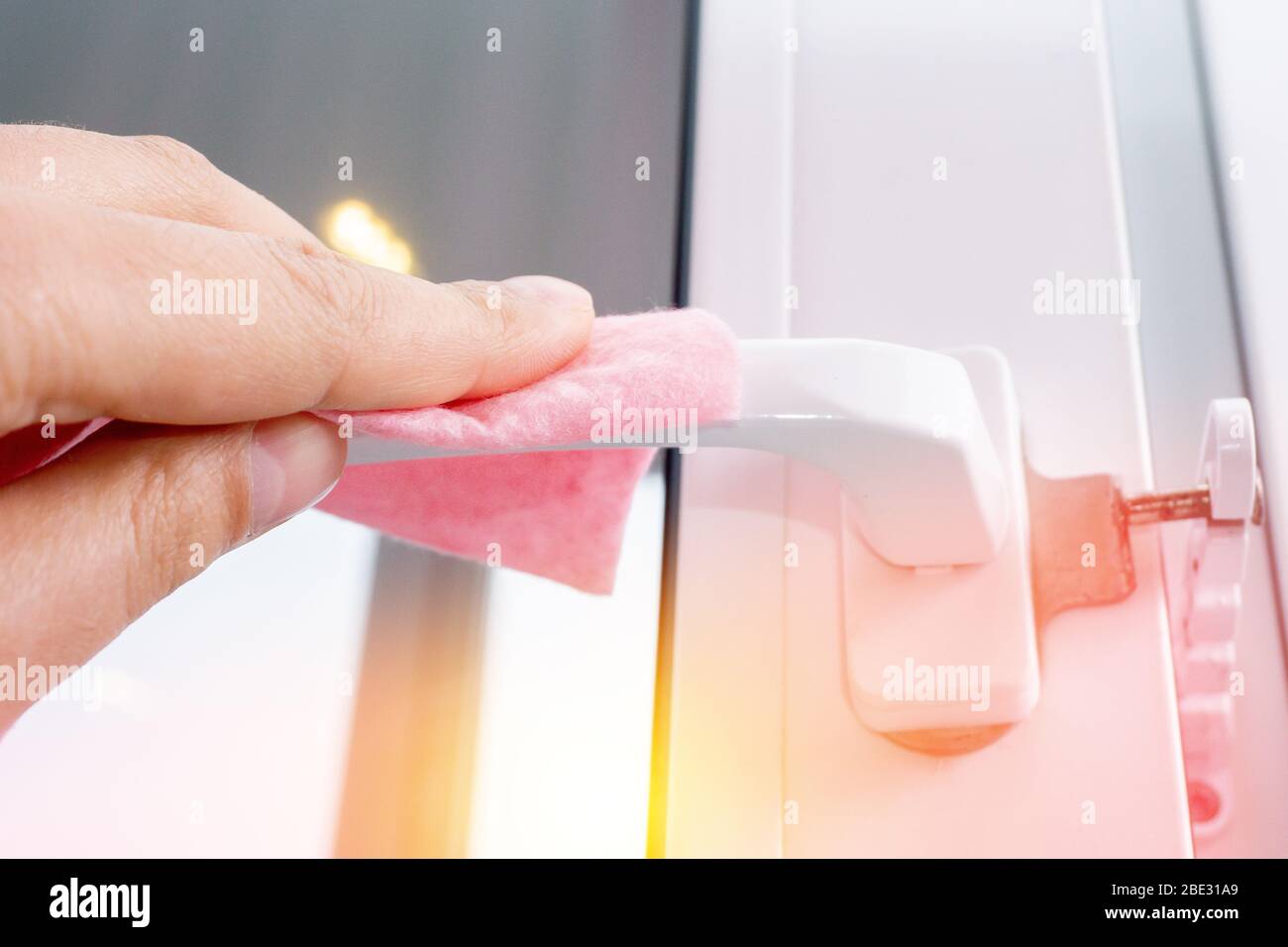 Strofinare la maniglia della porta dal balcone disinfettando l'igiene preventiva. Protegga la sua salute dal coronavirus. Foto Stock