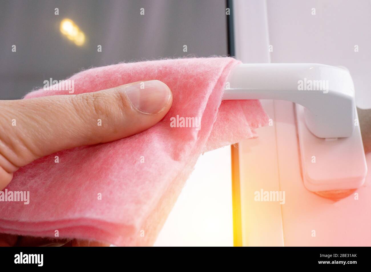 Strofinare la maniglia della porta dal balcone disinfettando l'igiene preventiva. Protegga la sua salute dal coronavirus. Foto Stock