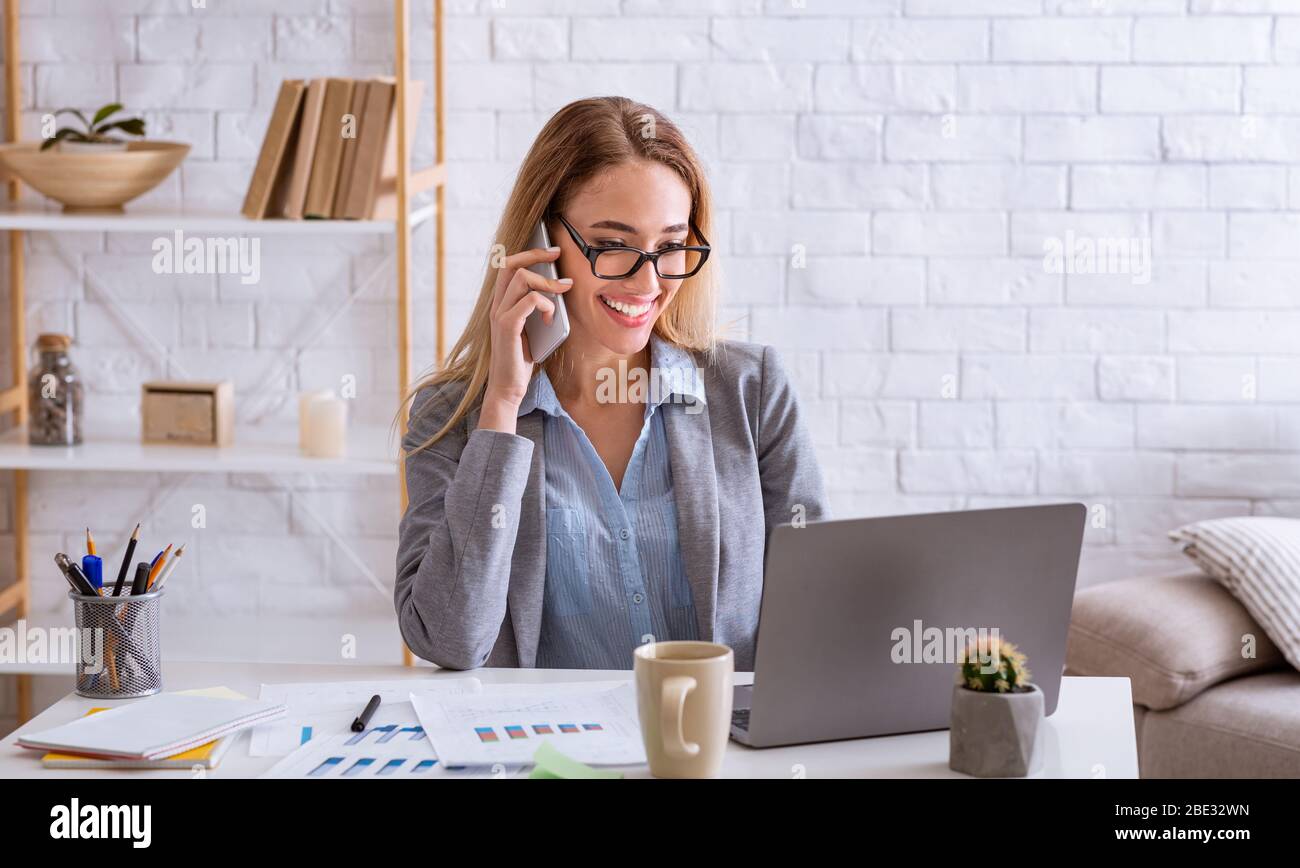 Donna d'affari che parla al telefono e guarda il notebook Foto Stock