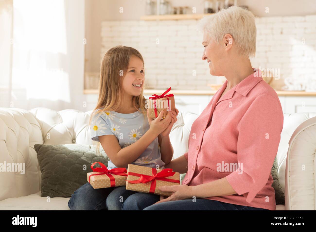 Festa di compleanno. Il bambino e la nonna che scambiano i regali di festa a casa Foto Stock