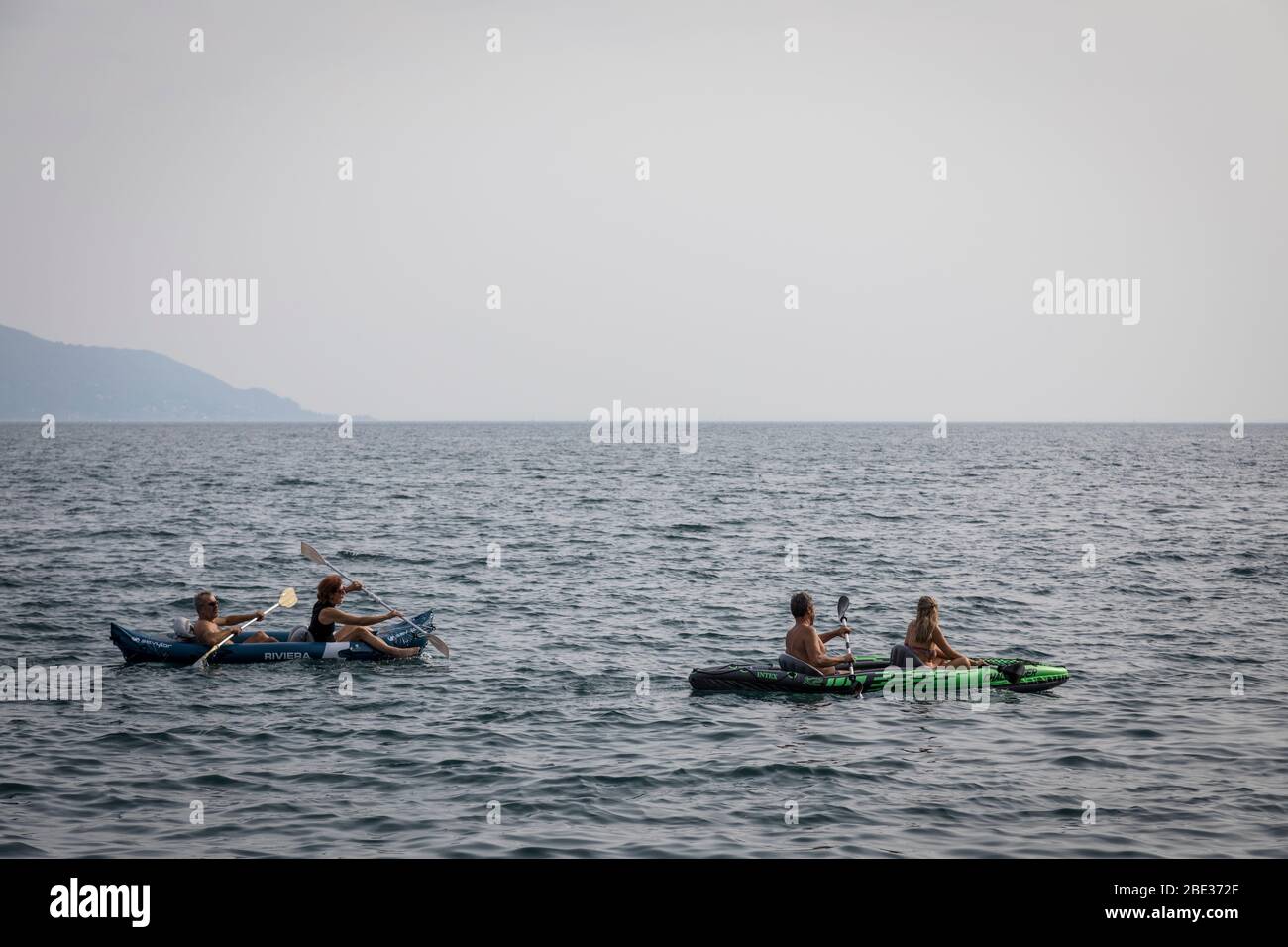 Due canoe doppie, ognuna con un uomo e una donna, pagaiano sul Lago di Garda, Italia. Foto Stock