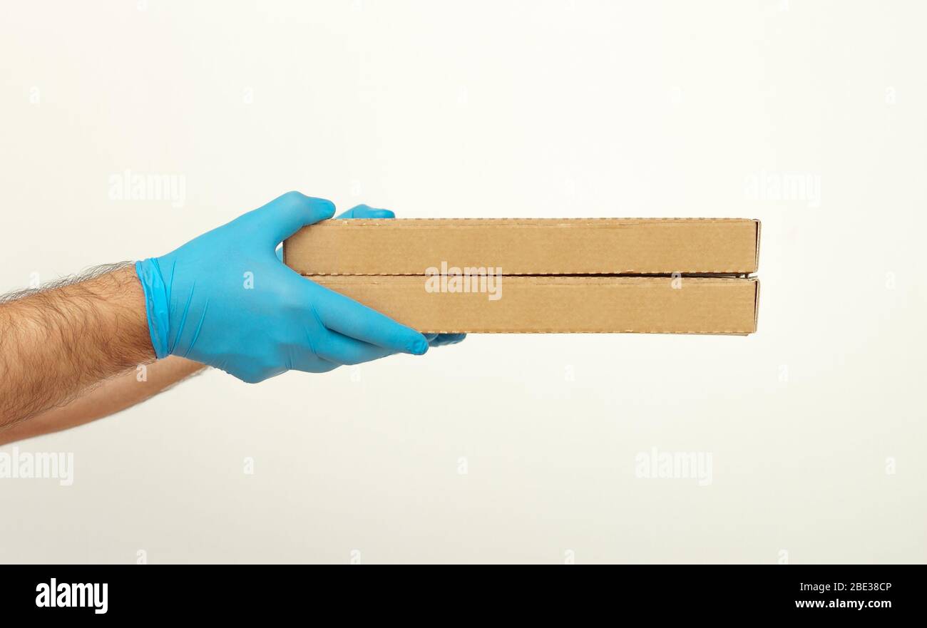 Consegna pizza. Le mani degli uomini nei guanti medici tengono le scatole della pizza. Quarantena di servizio influenza coronavirus pandemica 2019-ncov concetto. Covid-19 Foto Stock
