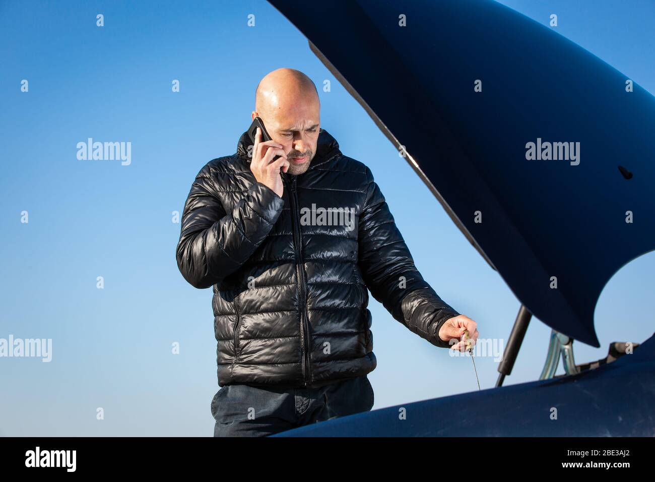 Uomo che chiede assistenza stradale, assistenza auto con la sua auto rotta dalla strada, problema auto, problema, trasporto Foto Stock