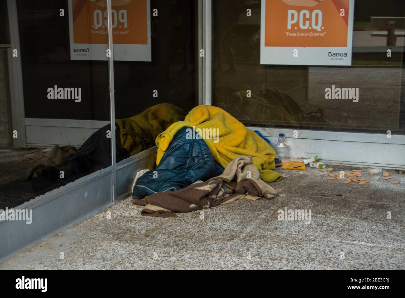 Un senzatetto che dorme davanti alla banca spagnola, Bankia durante la quarantena del coronavirus a Madrid, Spagna Foto Stock