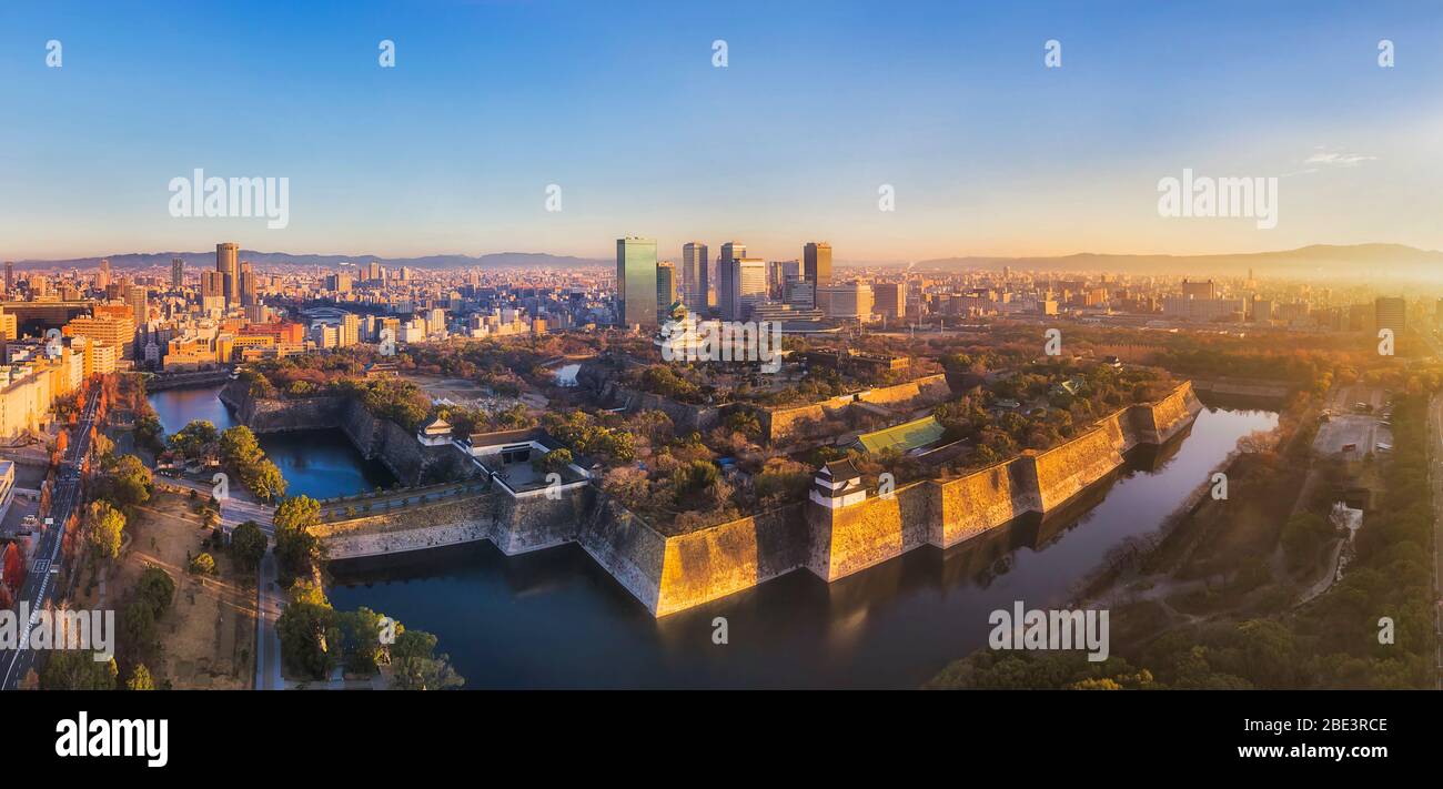 Scena aerea all'alba nella città giapponese di Osaka intorno a un parco storico con il vecchio castello e nuovi grattacieli moderni. Foto Stock