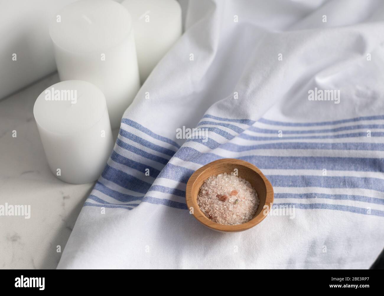 vasca da bagno con sale su lino su marmo con candele bianche Foto Stock