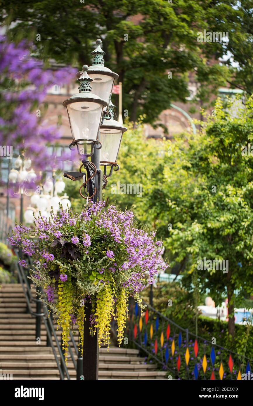 Fiori fioriti in estate decorano una lampada storica nel parco divertimenti dei Giardini di Tivoli a Copenhagen, Danimarca. Foto Stock