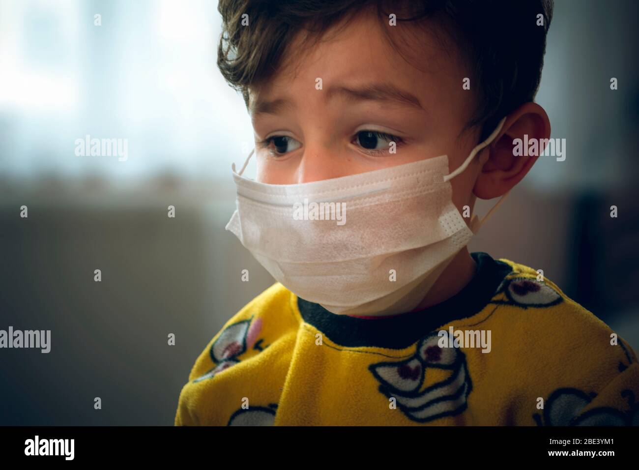 Bambino turco di 3 anni che indossa pigiama e maschera guardando tristemente ad un punto Foto Stock