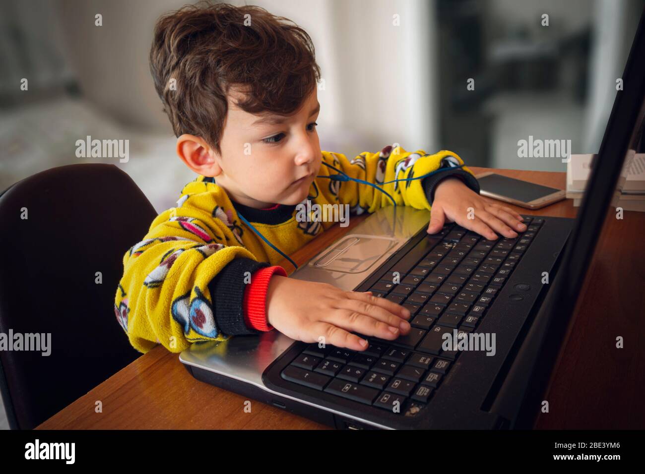 3 anni cute turco bambino indossare pigiama giallo guardando cartone animato da computer portatile Foto Stock