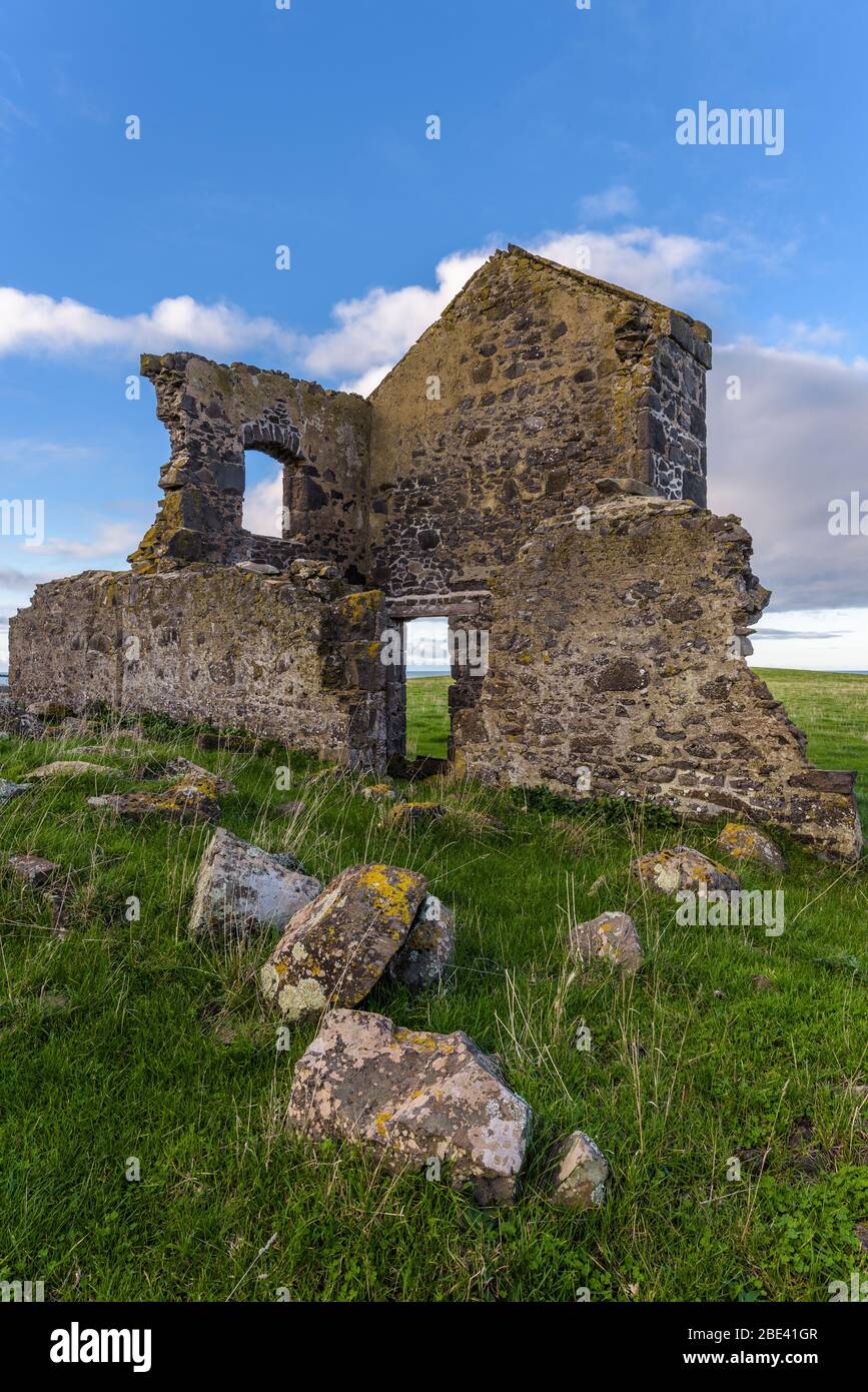 Prospettiva bassa di rovine del patrimonio su un cavoll erboso a Stanley, Tasmania in una giornata di overcast. Foto Stock