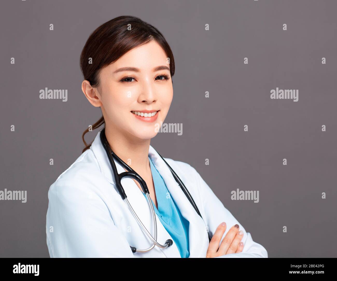 Medico femminile asiatico sorridente in cappotto bianco Foto Stock