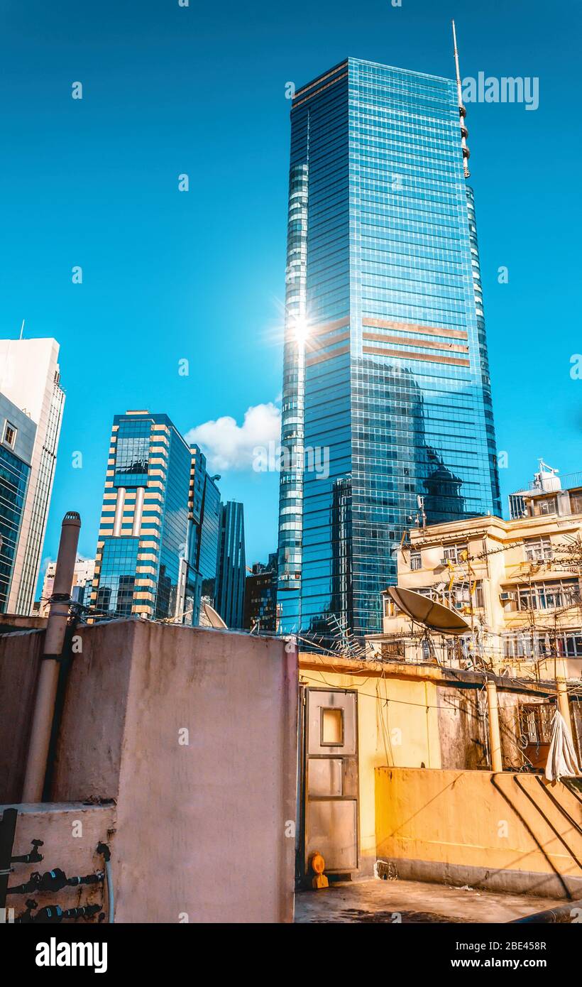 Alto e riflettente Skyscraper Blu in moderno Skyline sotto il Blue Sky e il Sole, Hong Kong Foto Stock