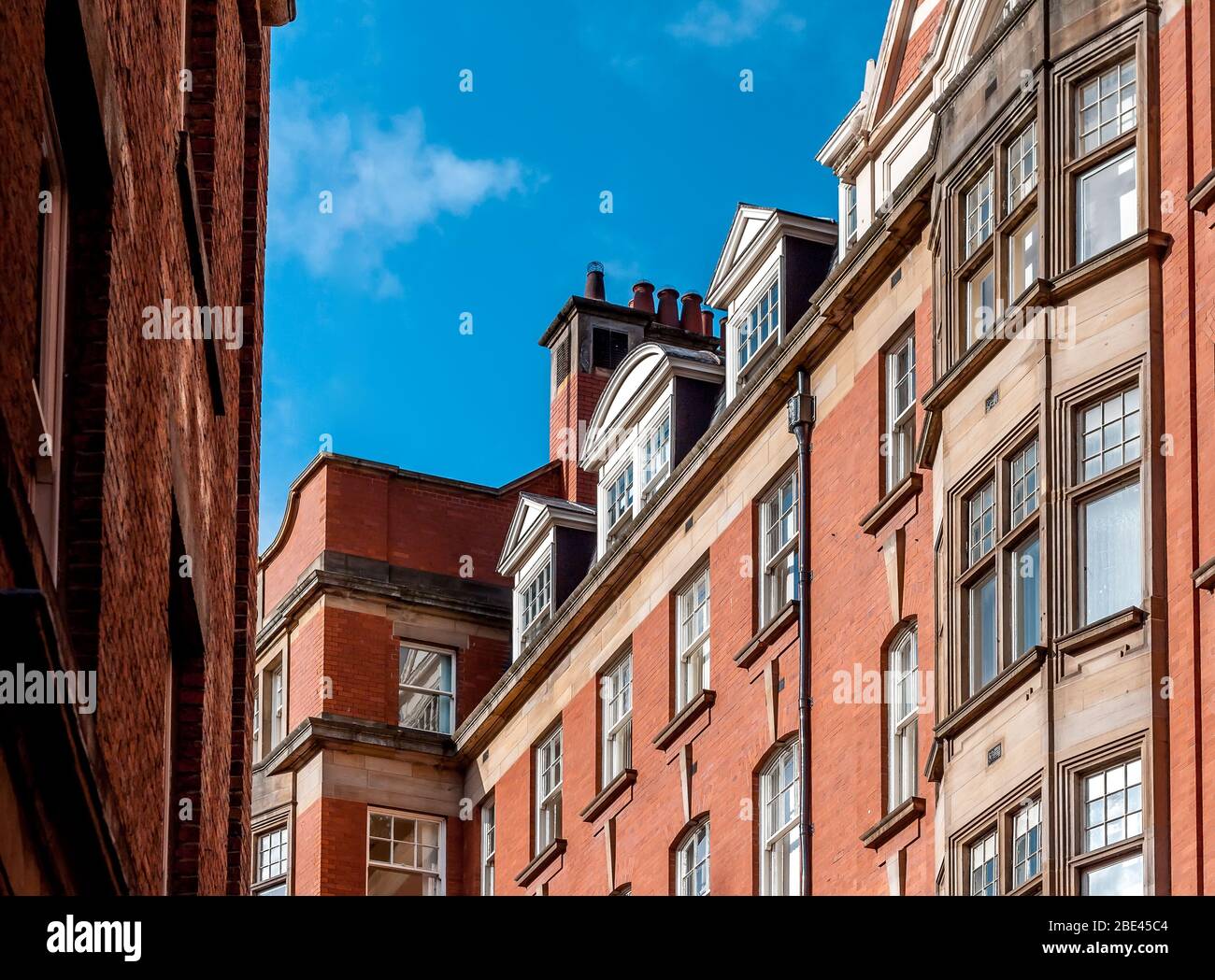 Facciata di tradizionale British Red Brick Architecture lungo la strada sotto il cielo blu a Newcastle upon Tyne, Regno Unito Foto Stock