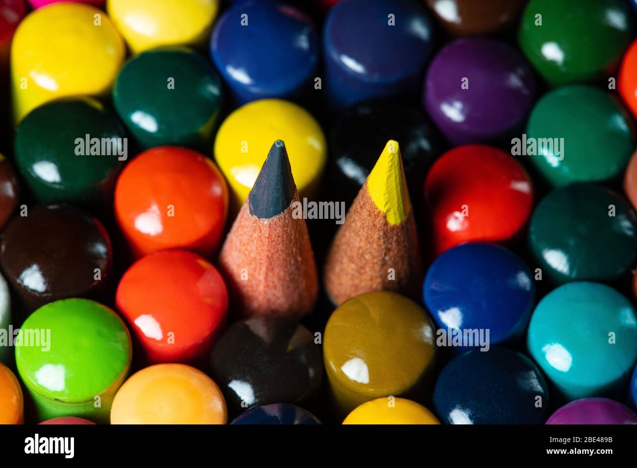 Immagine macro di un set di matite colorate dell'artista in una tazza strettamente raggruppate con le spalle rivolte verso l'alto con una matita gialla e una grigia suggerimenti poking per fro Foto Stock