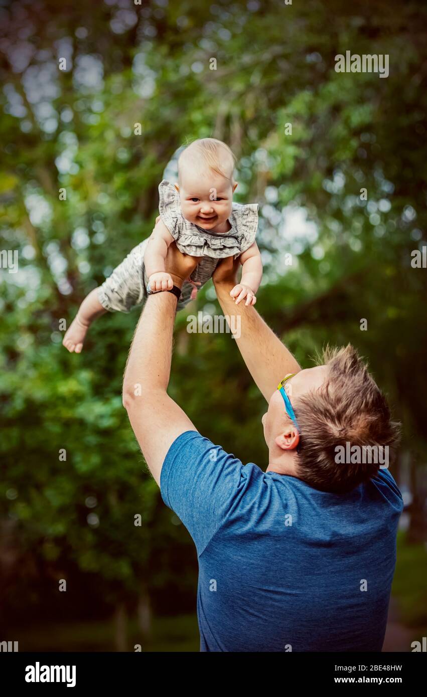 Un padre che tiene la sua bambina nell'aria mentre all'aperto durante la caduta; Edmonton, Alberta, Canada Foto Stock