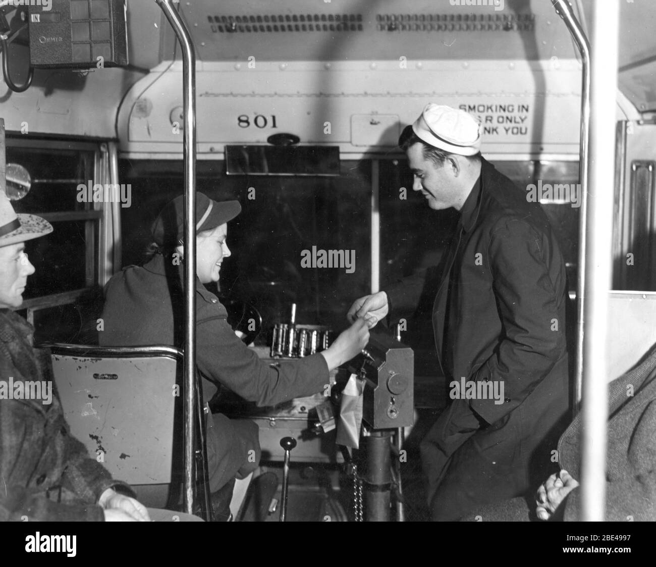 "Donne nei servizi essenziali - le donne che guidano autobus aiutano ad accelerare i problemi di trasporto dell'America (febbraio 1943)" così dice il testo sulla fotografia della Sig.ra Ann Rosener, preso per 'l'Ufficio delle informazioni di guerra.' Un bell'esempio di come le donne della nostra nazione hanno assunto innumerevoli posti di lavoro lasciati vuoti da uomini andati in guerra. Prima della seconda Guerra Mondiale, le donne semplicemente non hanno fatto guidare gli autobus urbani. Nota le pile di monete, pronte a fornire il cambio per i passeggeri, come il marinaio amichevole che paga la nostra ragazza felice autista. Nota: "Solo posteriore. Grazie." Per vedere le altre immagini di trasporto, Cerca: Prestor veicolo d'epoca Foto Stock