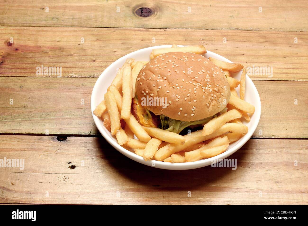 Hamburger di formaggio con pancetta e patatine su sfondo di legno Foto Stock