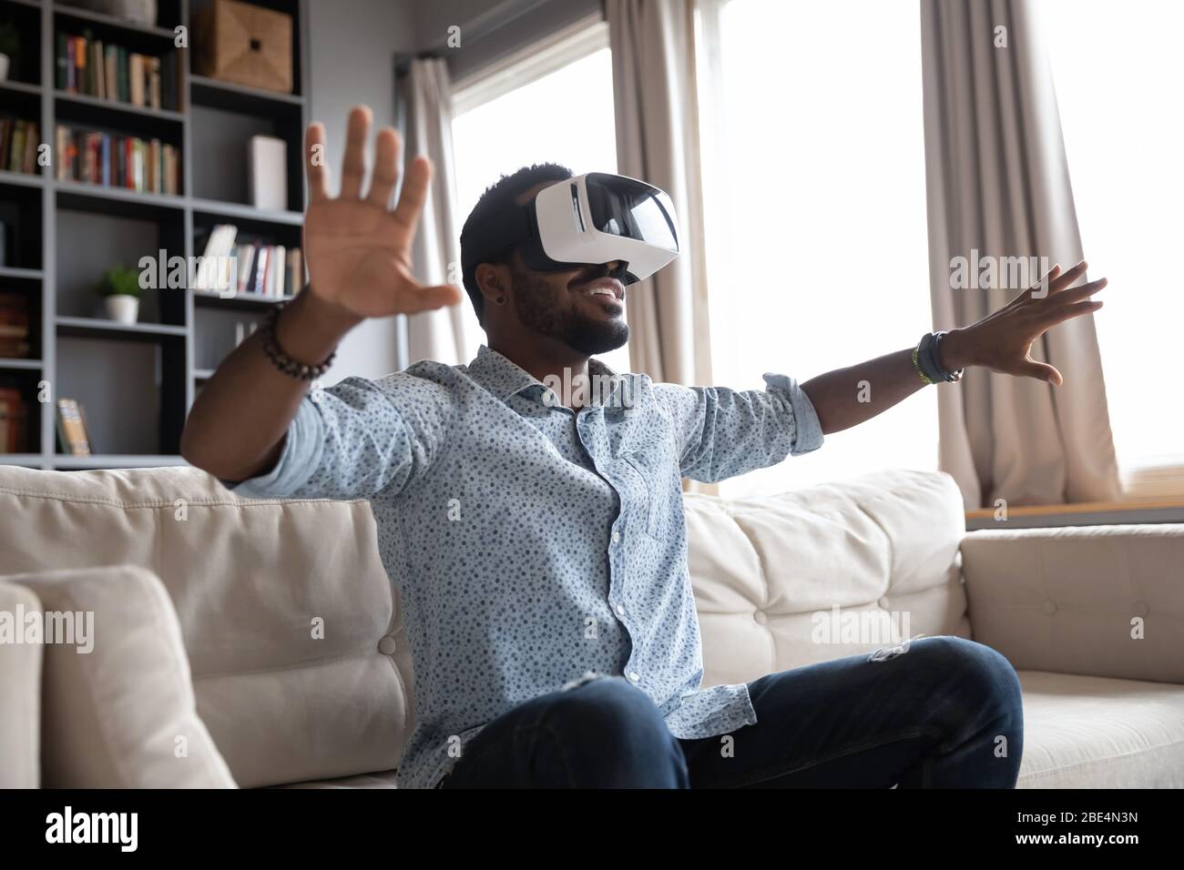 Giovane ragazzo con gioia che si divertiva a passare il tempo in realtà virtuale. Foto Stock