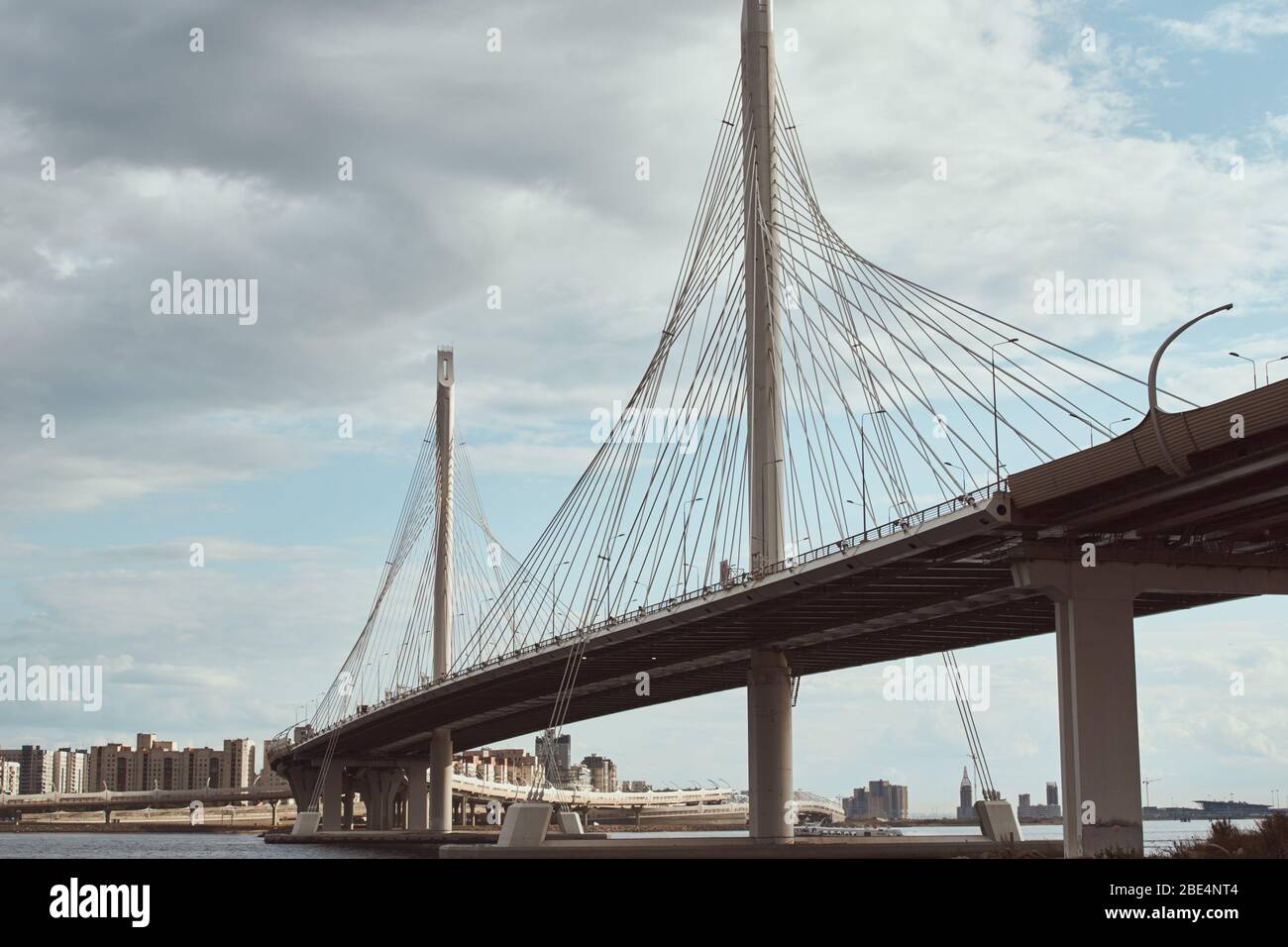 il cavo moderno ha sospeso il ponte sul fiume contro il cielo nuvoloso. Primo piano per la costruzione di ingegneria Foto Stock