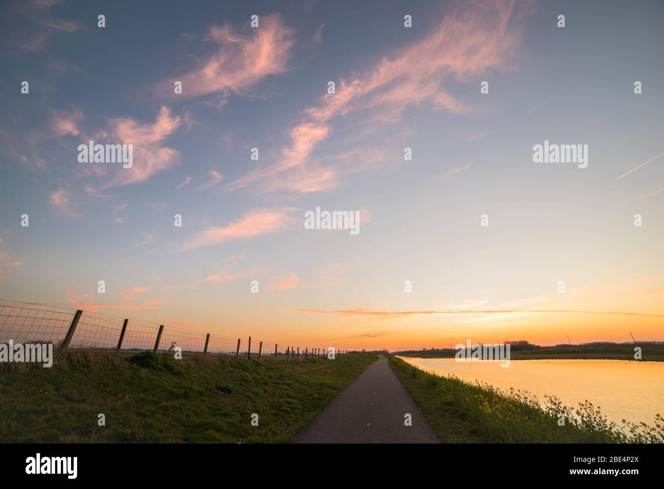 Il sentiero lungo un fiume sta svanendo in lontananza. Bei colori delle nuvole subito dopo il tramonto. Foto Stock