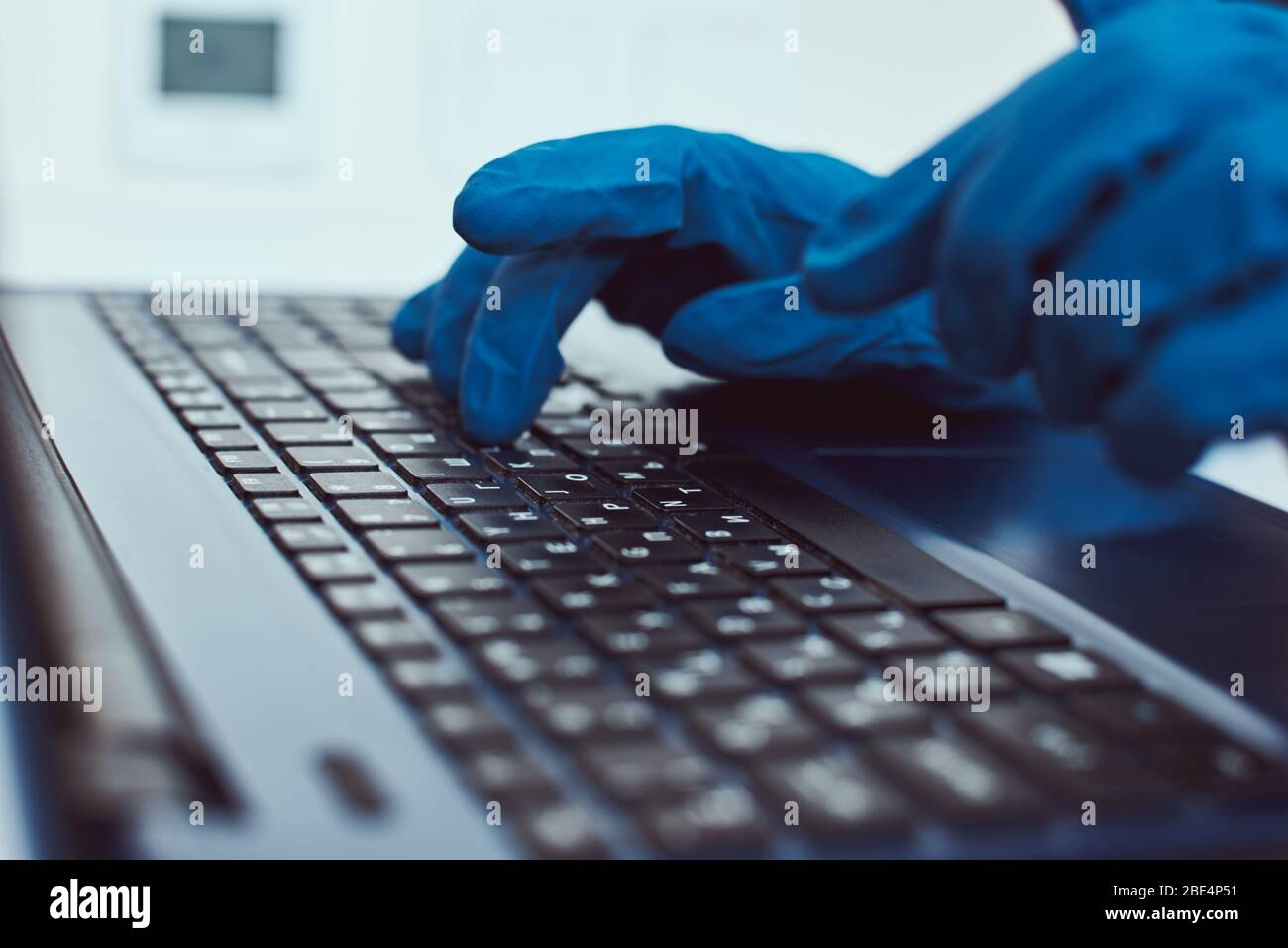 Indossare guanti protettivi sulla tastiera del notebook. Cyber criminalità e protezione delle informazioni Foto Stock