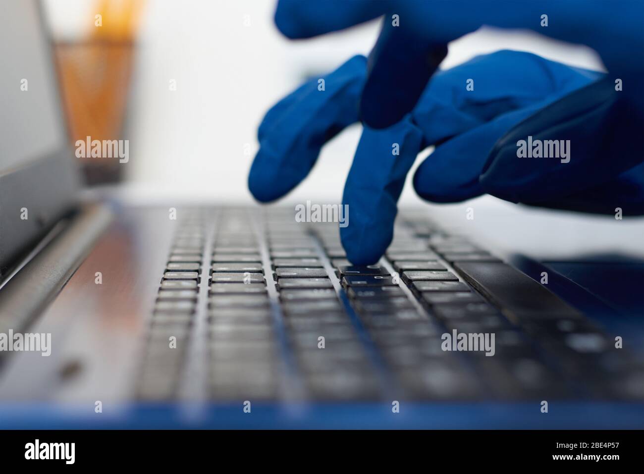 Indossare guanti protettivi sulla tastiera del notebook. Cyber criminalità e protezione dei dati e informazioni Foto Stock