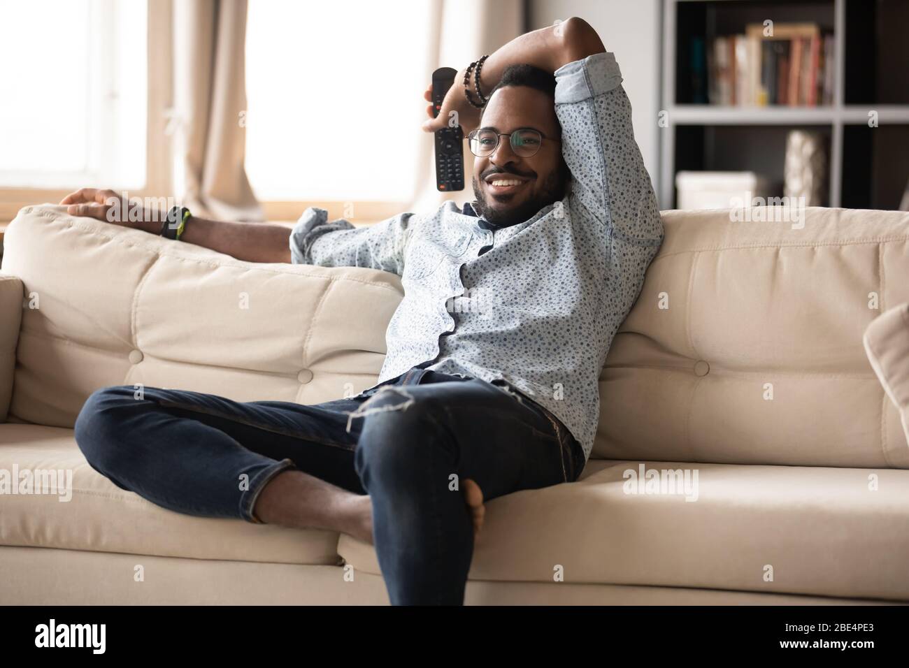 Felice bel giovane etnia africana che guarda programmi televisivi. Foto Stock