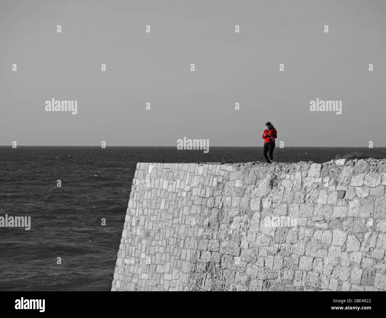 Lone ragazza che usa il suo telefono per ascoltare musica mentre cammina in riva al mare. Concetto : minimalismo in fotografia, solitudine. Foto Stock