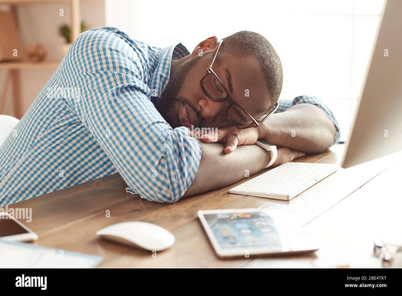 Fare una pausa. Uomo afro americano stanco in bicchieri che dormono nel suo posto di lavoro a casa. Afro americano uomo d'affari sensazione esaurito e dormire al lavoro. Freelance. Lavoro da ufficio domestico Foto Stock
